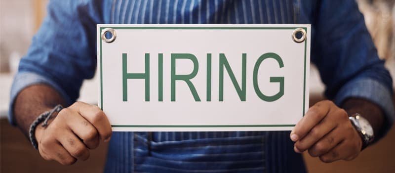 Business owner holding a hiring sign